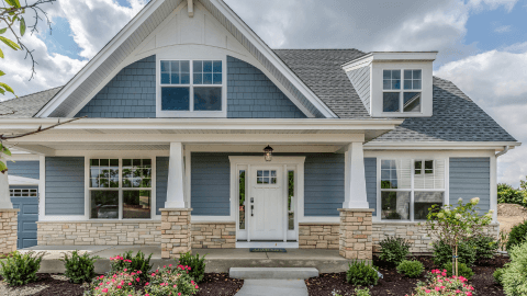 Completed blue siding job on a craftsman-style home with covered porch