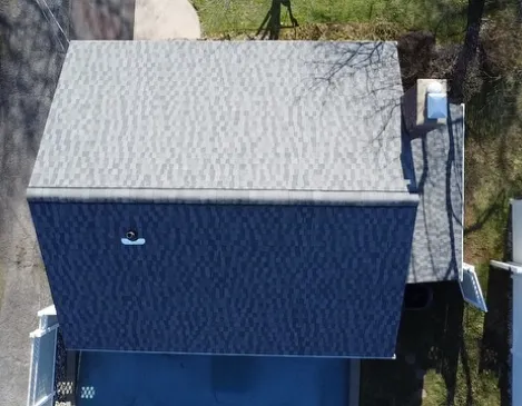 Aerial view of a finished shingle roof over a home with an in-ground pool
