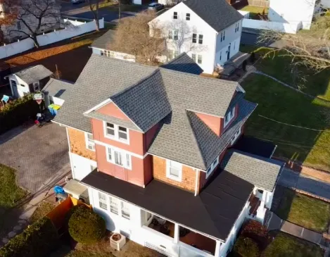 Aerial view of a finished shingle roof on a two-story brick home with a dormer