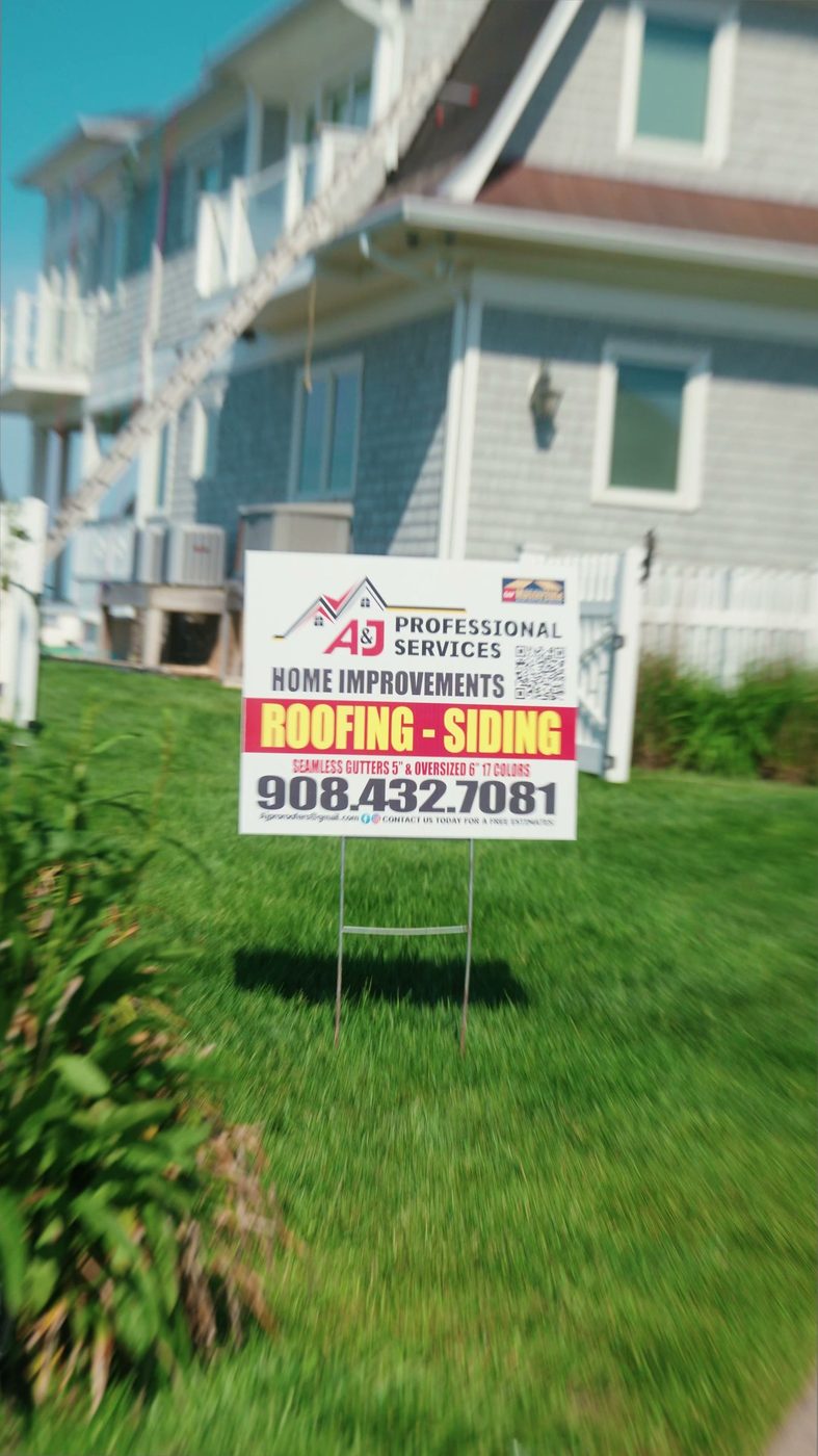 An A and J Professional Services yard sign on the lawn of a house being worked on