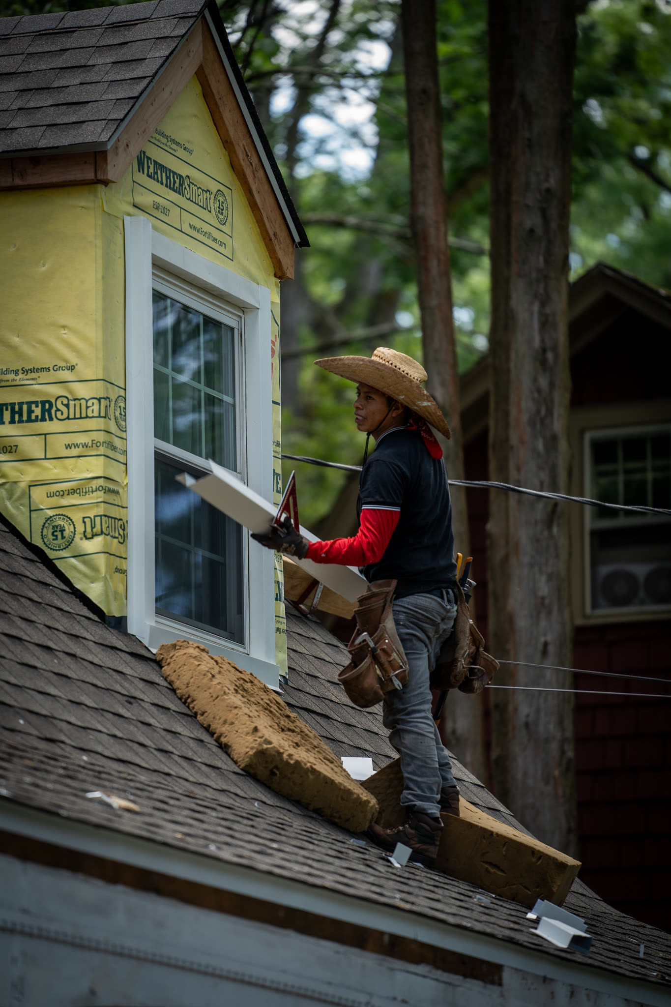 A&J crew fitting window trim over new house wrap during an active siding job